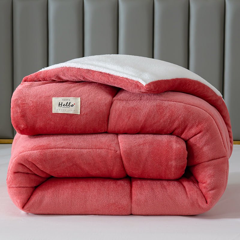 Pink weighted blanket with a label on a bed against a gray headboard.