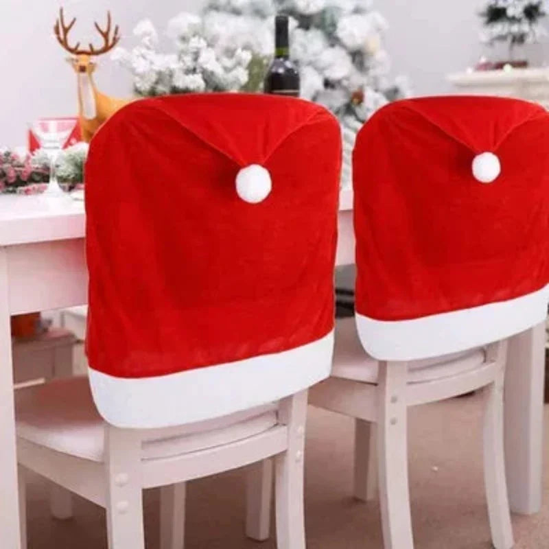 SantaSeat chair covers with white trim and pom poms on dining chairs near a reindeer decoration